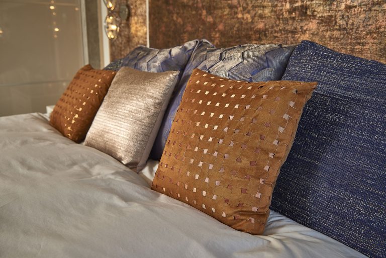 Cushions in copper, bronze and navy on the bed