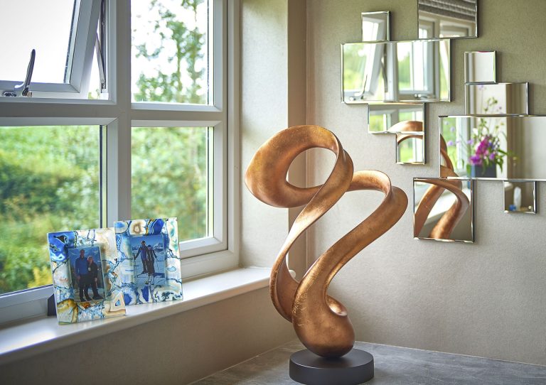Bronze sculpture and fused glass pieces on a window sill