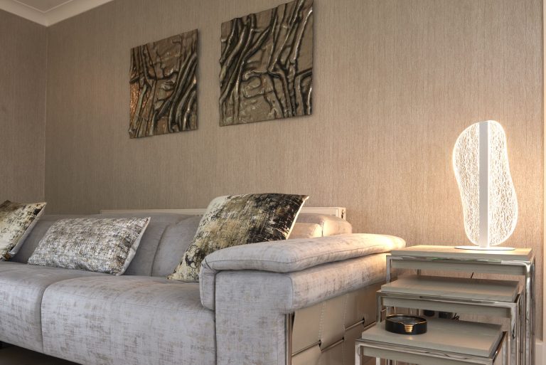 Lounge in warm neutrals with glass wall art and a garden view